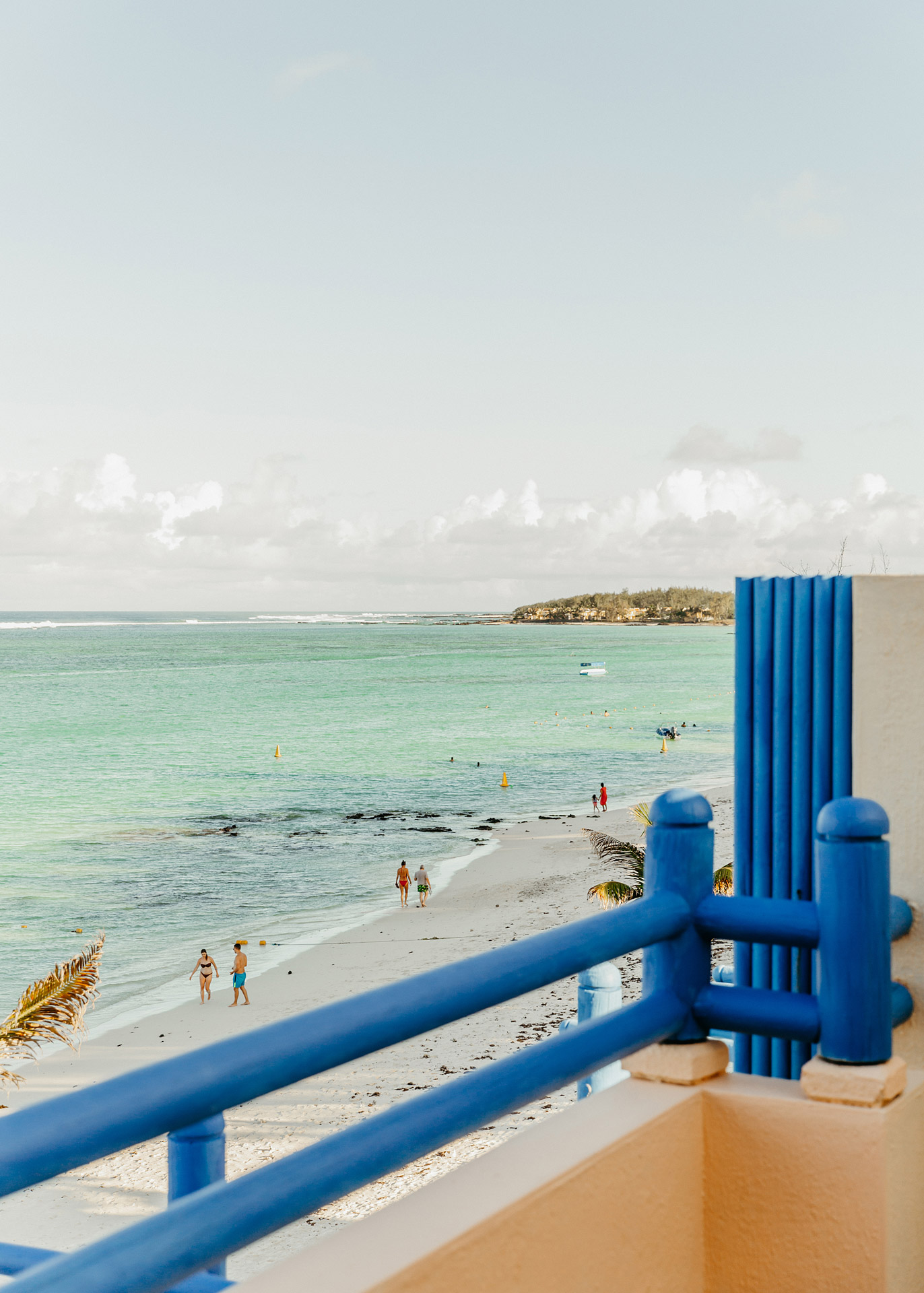 Coastal view from a private balcony overlooking the beach and turquoise sea.