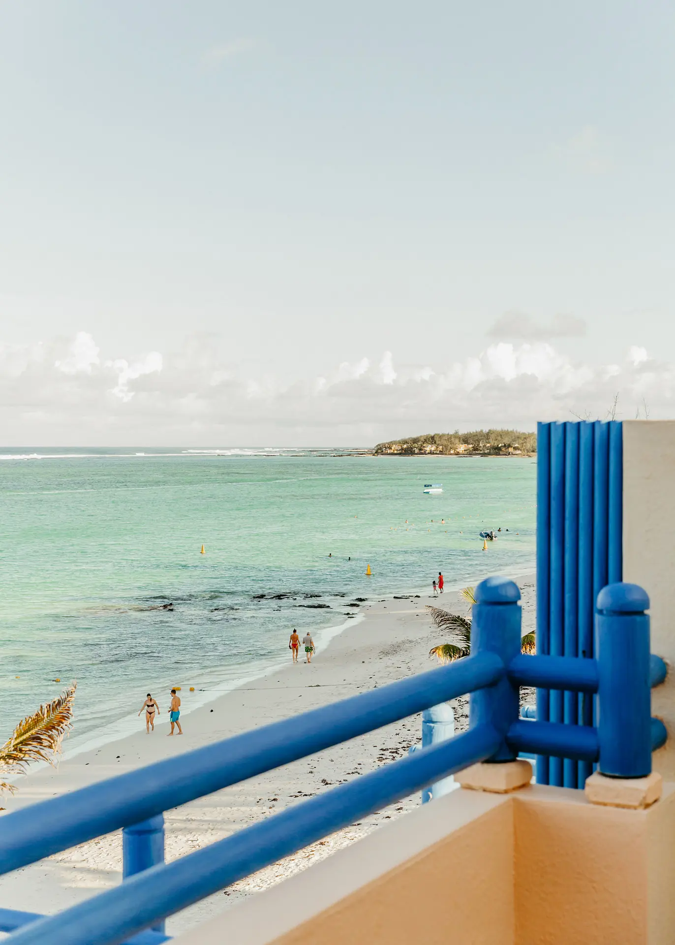 Coastal view from a private balcony overlooking the beach and turquoise sea.