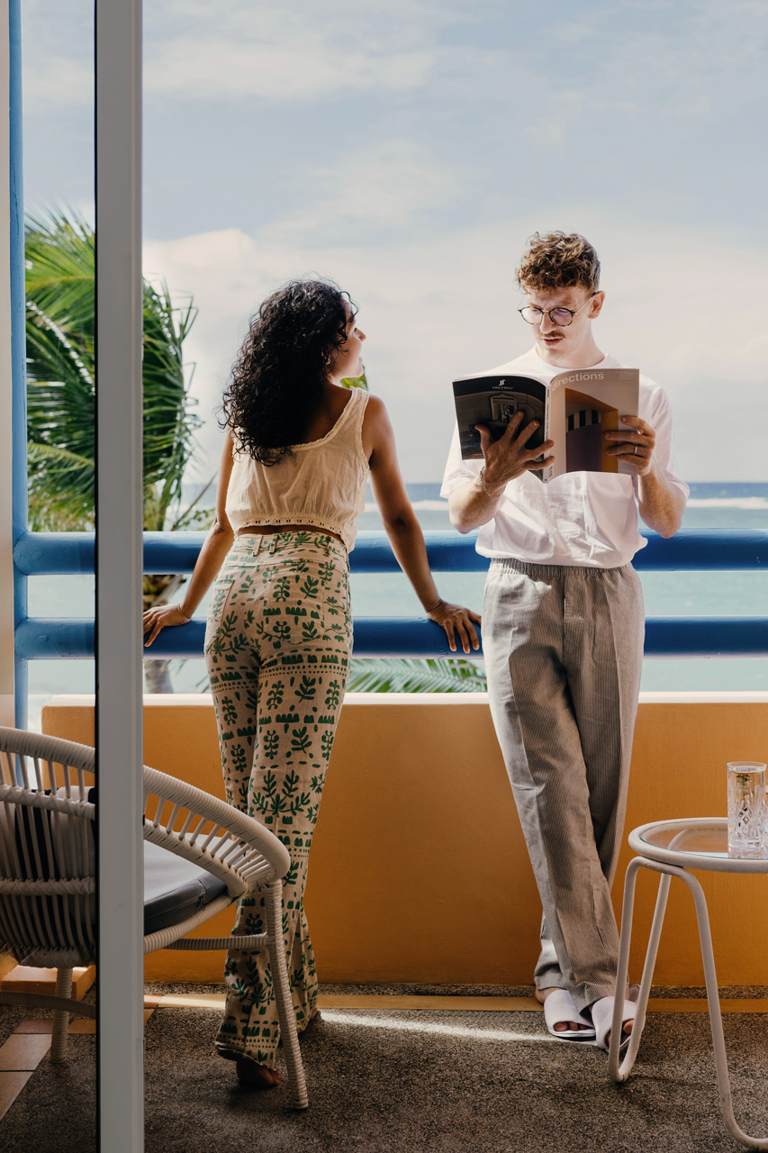 Couple relaxing on a private hotel balcony overlooking the ocean.
