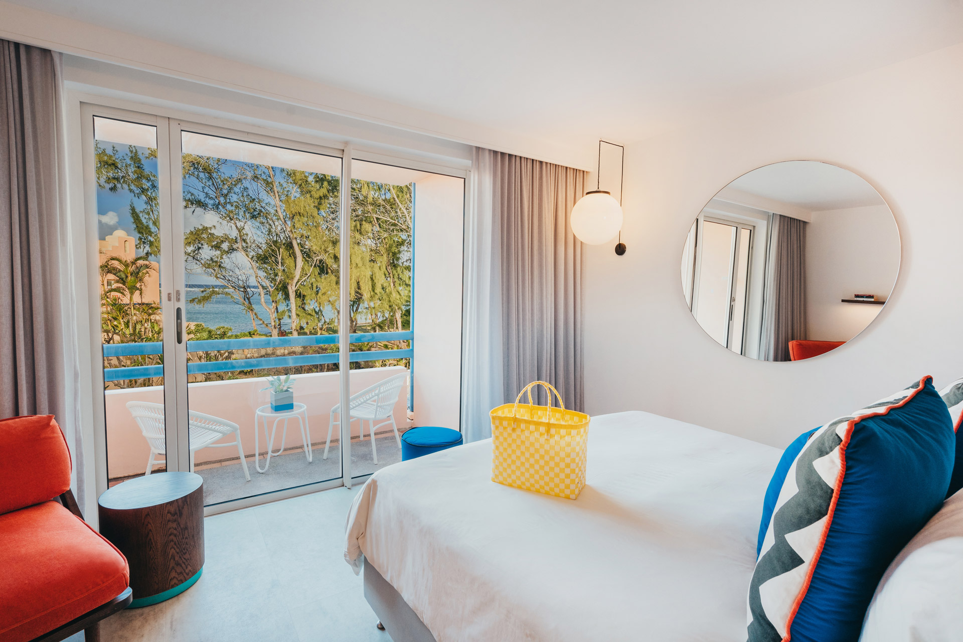 Bright bedroom with a private balcony overlooking tropical gardens.