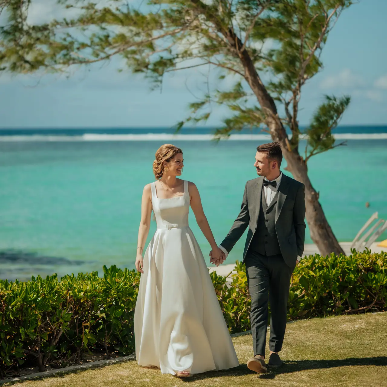 Newlyweds strolling hand in hand by the lagoon.