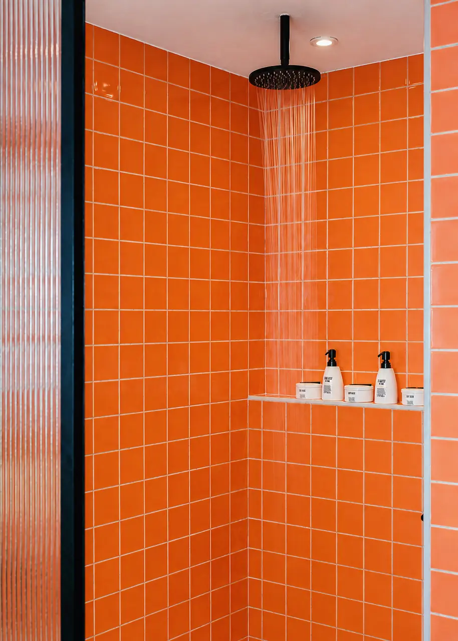Rainfall shower with vibrant terracotta tiles and refillable bathroom amenities.