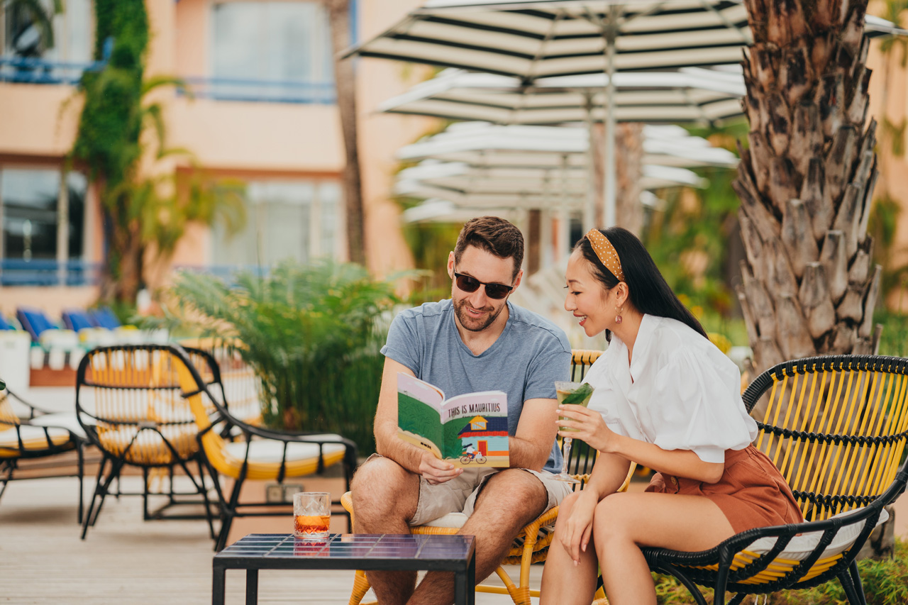 Couple lisant et savourant un verre au bord de la piscine.