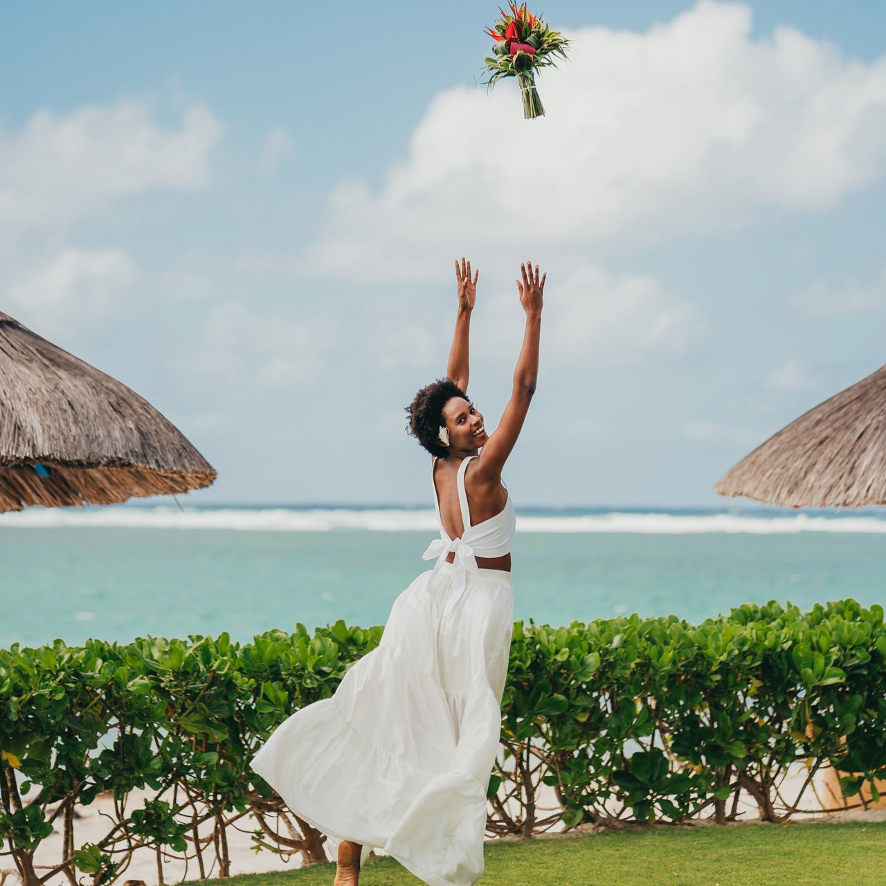 Bride tossing her bouquet by the tropical gardens.
