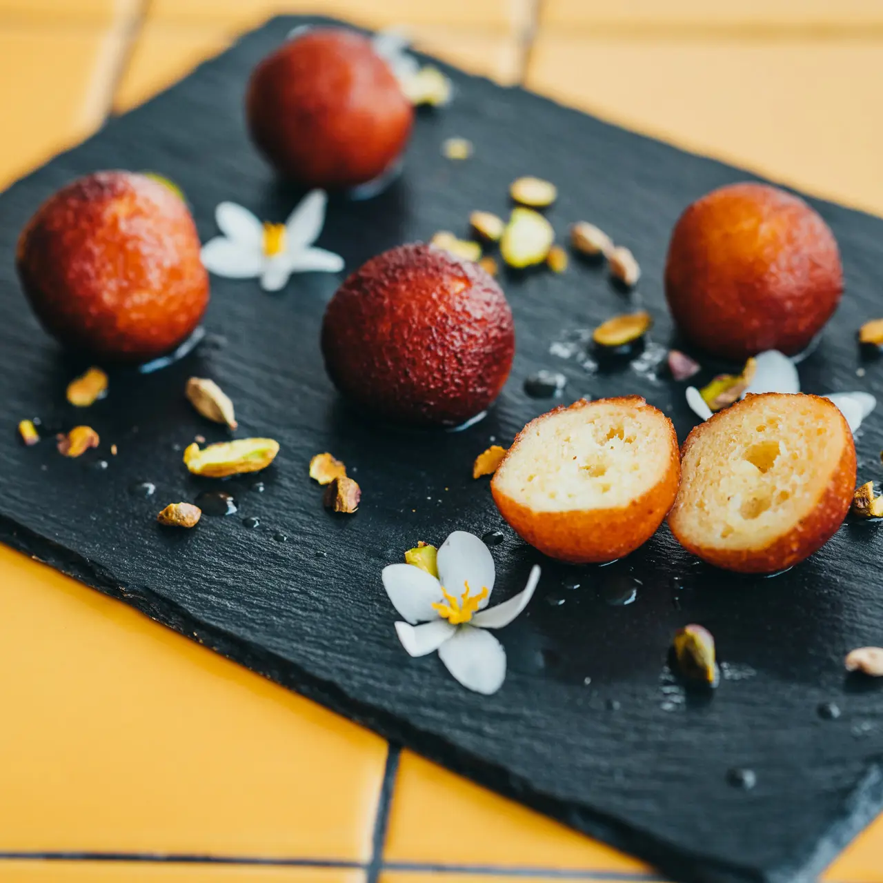 Rasgullah with pistachios and edible flowers.
