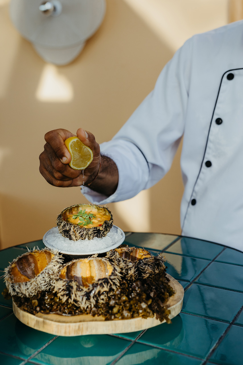 Chef adding lemon to fresh sea urchins.