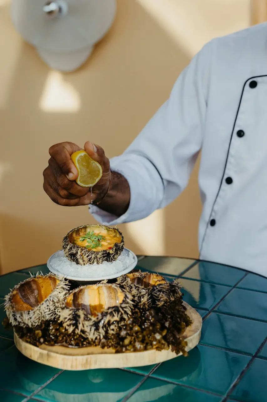 Chef ajoutant du citron à des oursins frais.