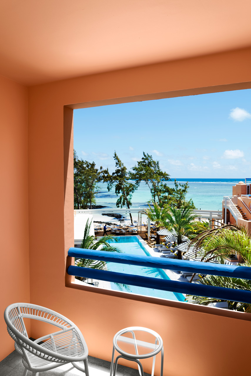 Balcony overlooking the pool, palm trees and turquoise lagoon by the sea.