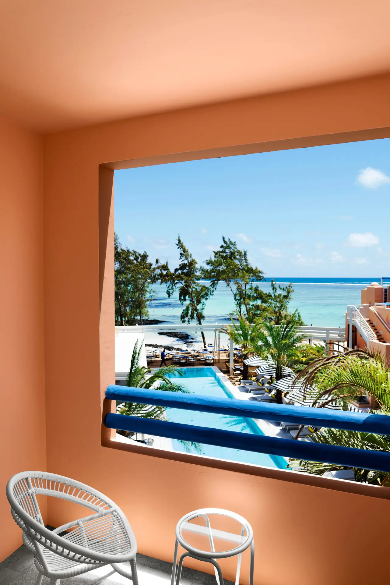 Private hotel balcony overlooking the pool, tropical gardens, and the turquoise ocean beyond.