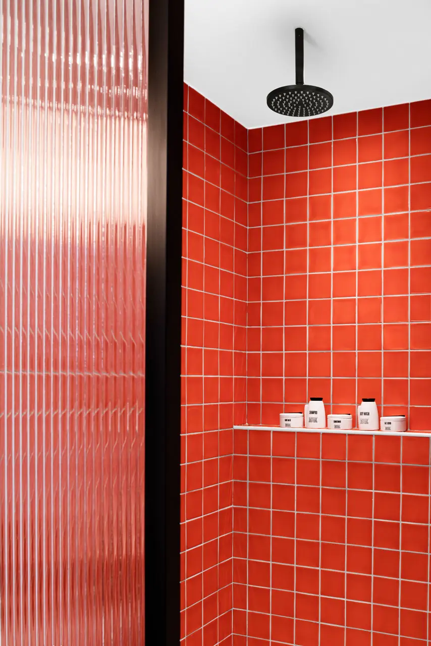 Rainfall shower with vibrant terracotta tiles and refillable bathroom amenities.