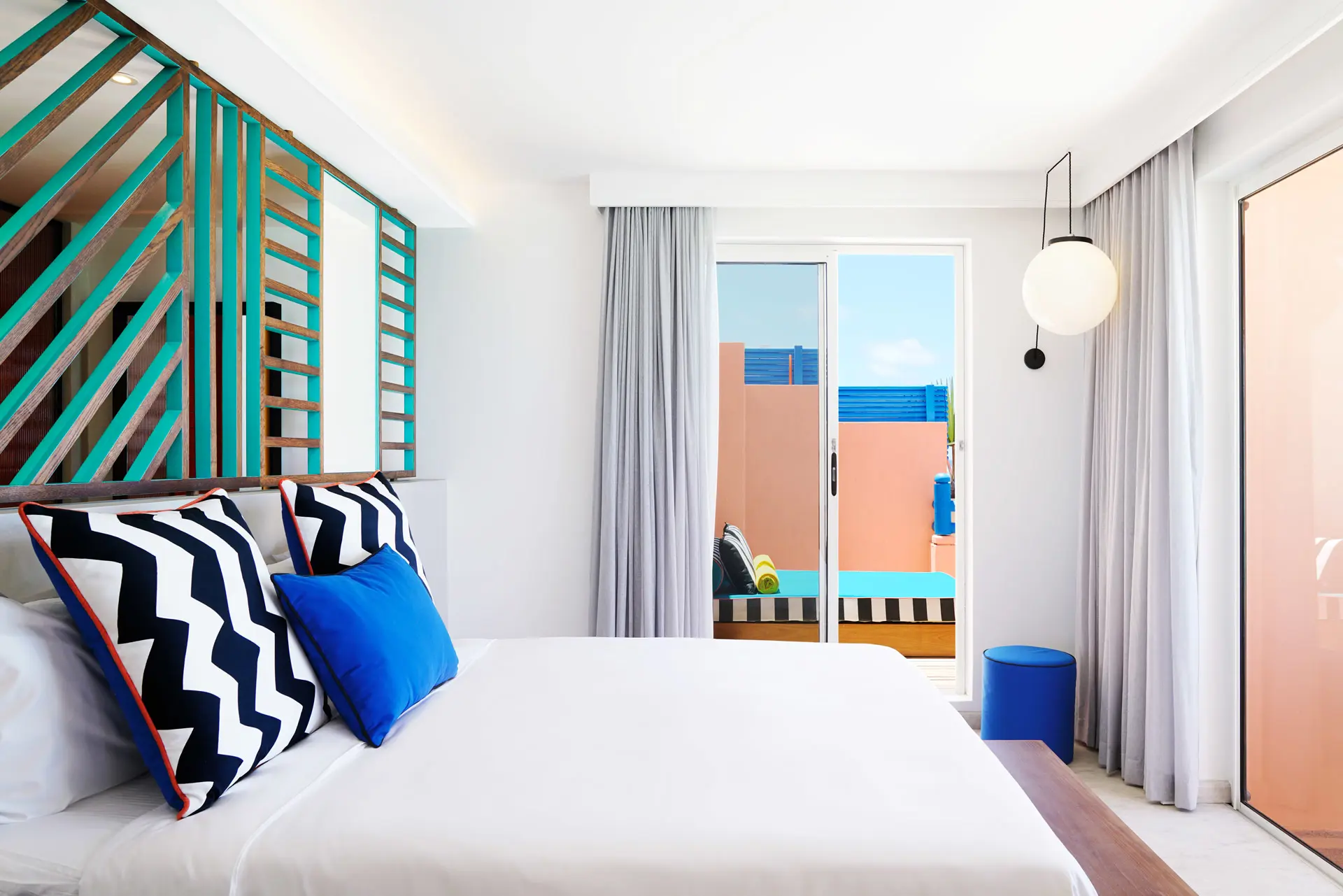 Bright hotel bedroom with a king-size bed and private terrace featuring an outdoor daybed.