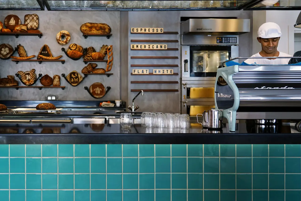 Comptoir café avec pains artisanaux en vitrine.