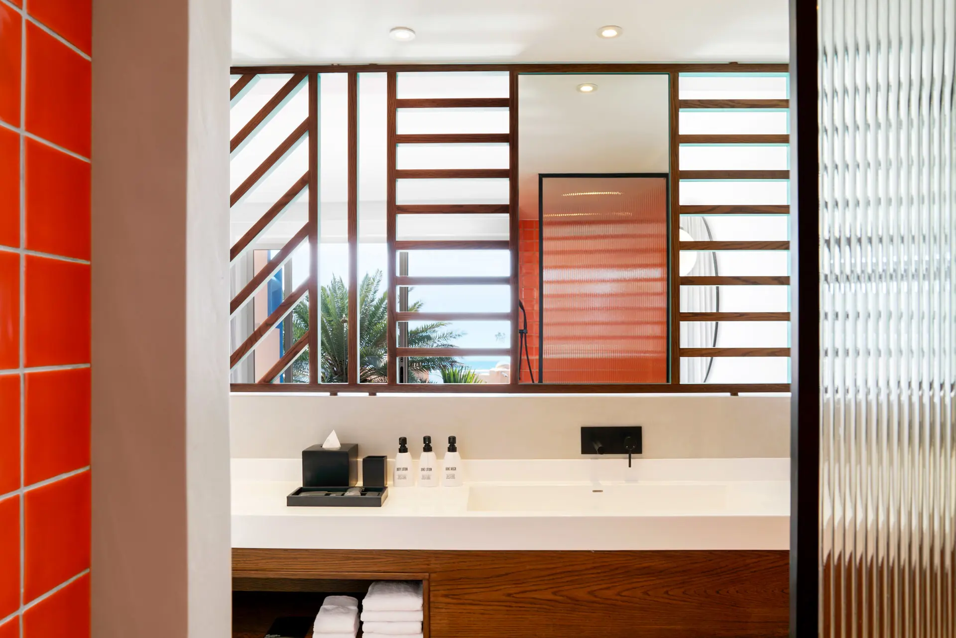 Contemporary hotel bathroom with a spacious vanity, open-plan design, and natural wood accents.