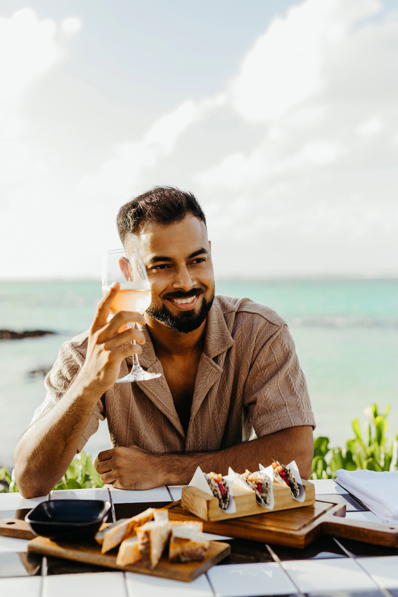 Homme savourant un déjeuner et un verre de vin face à l’océan au Tek Tek.