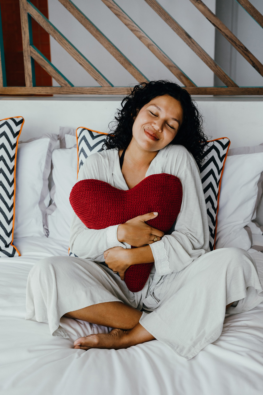 Guest relaxing on a bed with a heart-shaped cushion.