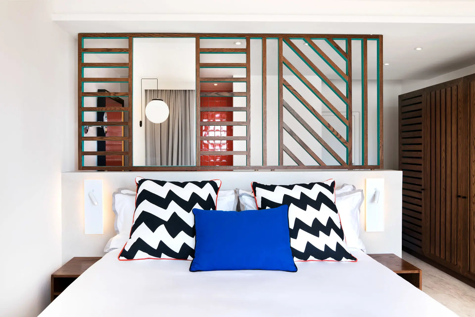 Contemporary hotel room with a king-size bed, bold geometric décor, and an open-plan layout.