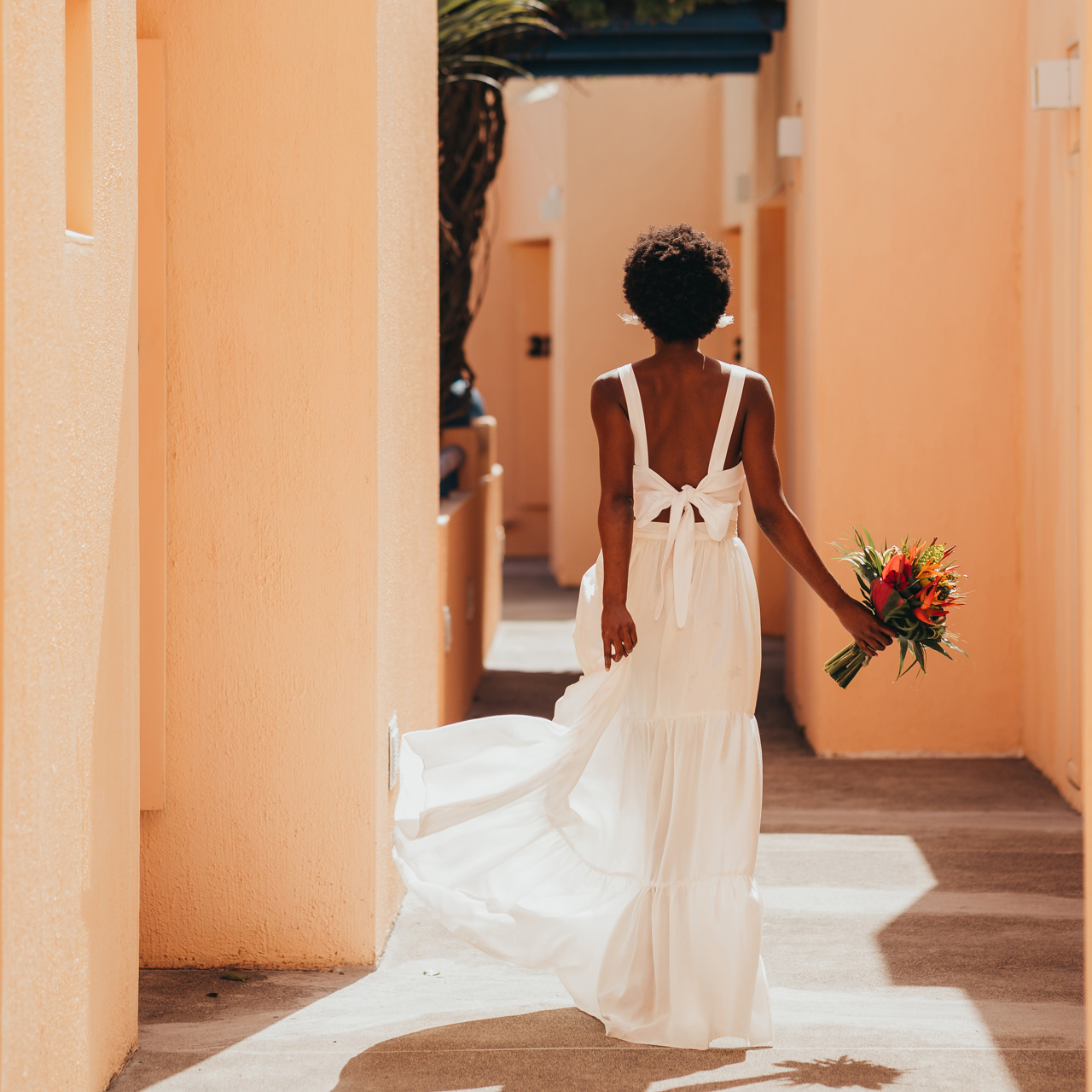 Bride walking through the resort with a tropical bouquet.