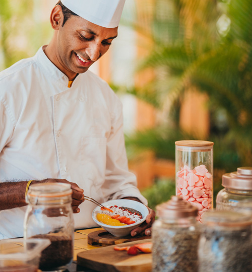 Chef preparing a raw fruit breakfast bowl.