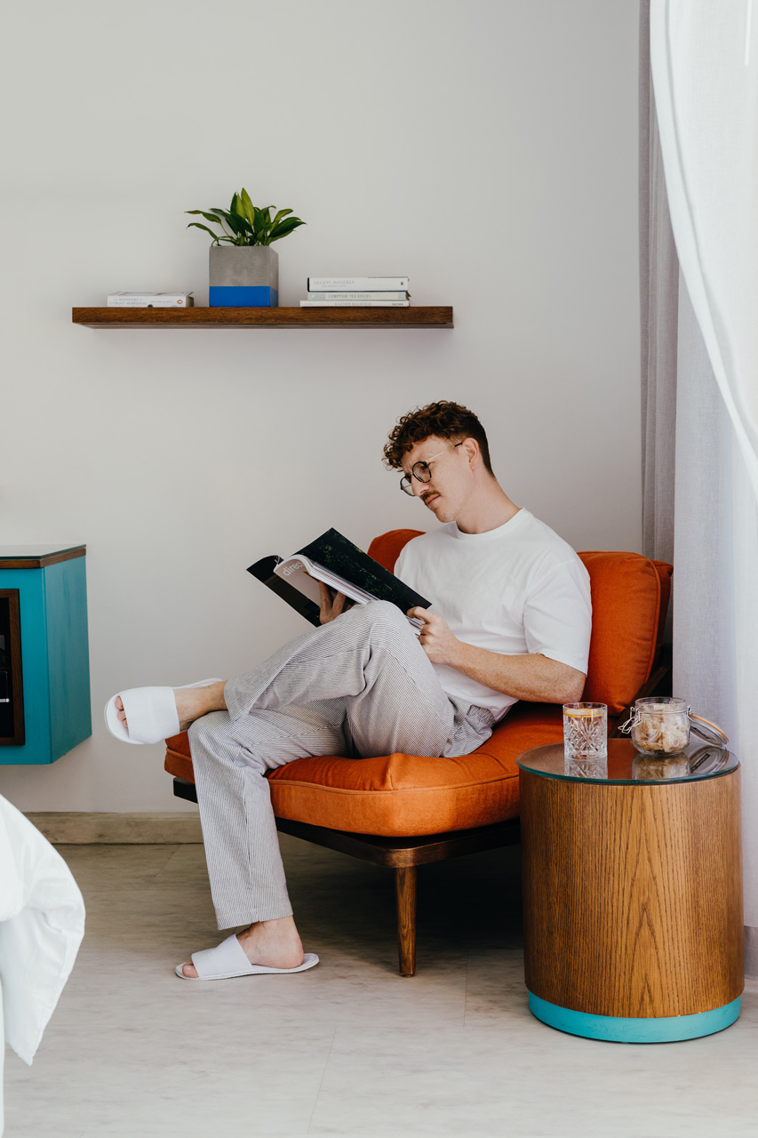 Guest relaxing with a book in a bright, modern room.