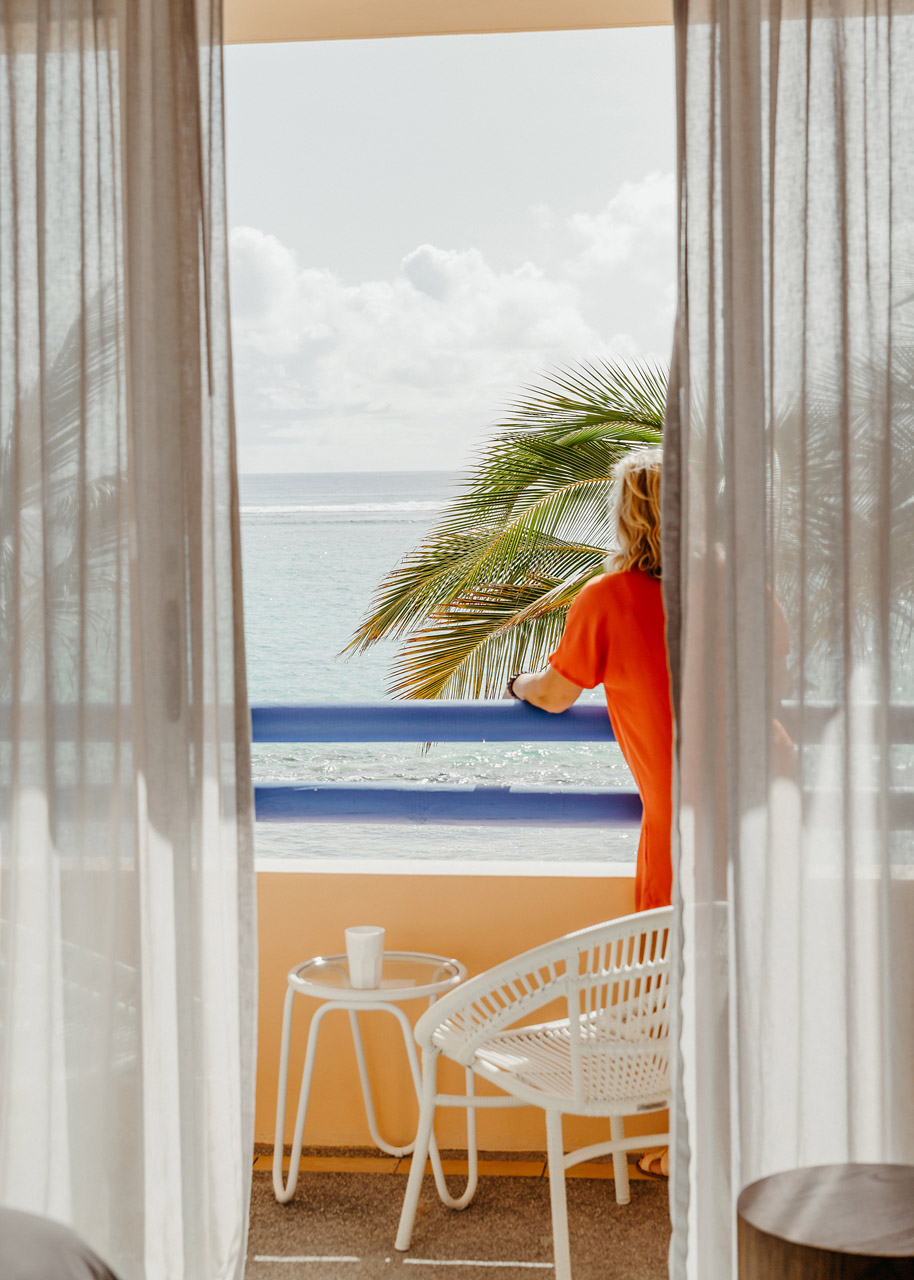 Guest enjoying ocean views from a private balcony framed by tropical palms.