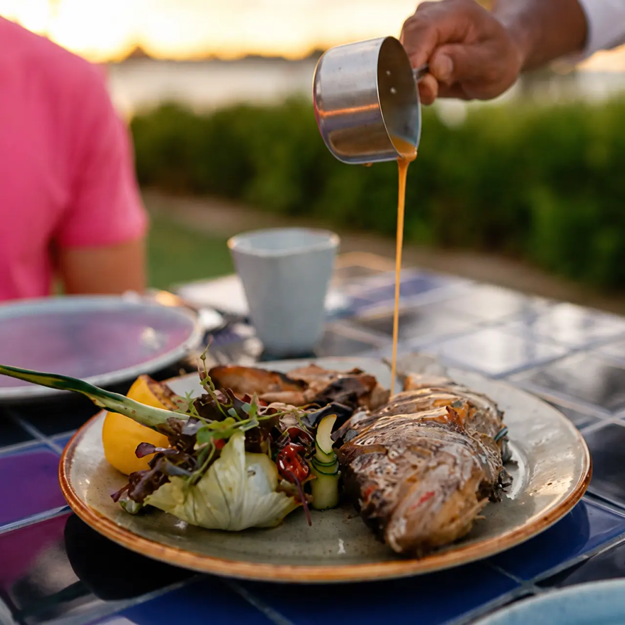 Freshly grilled whole fish served with seasonal vegetables and sauce.