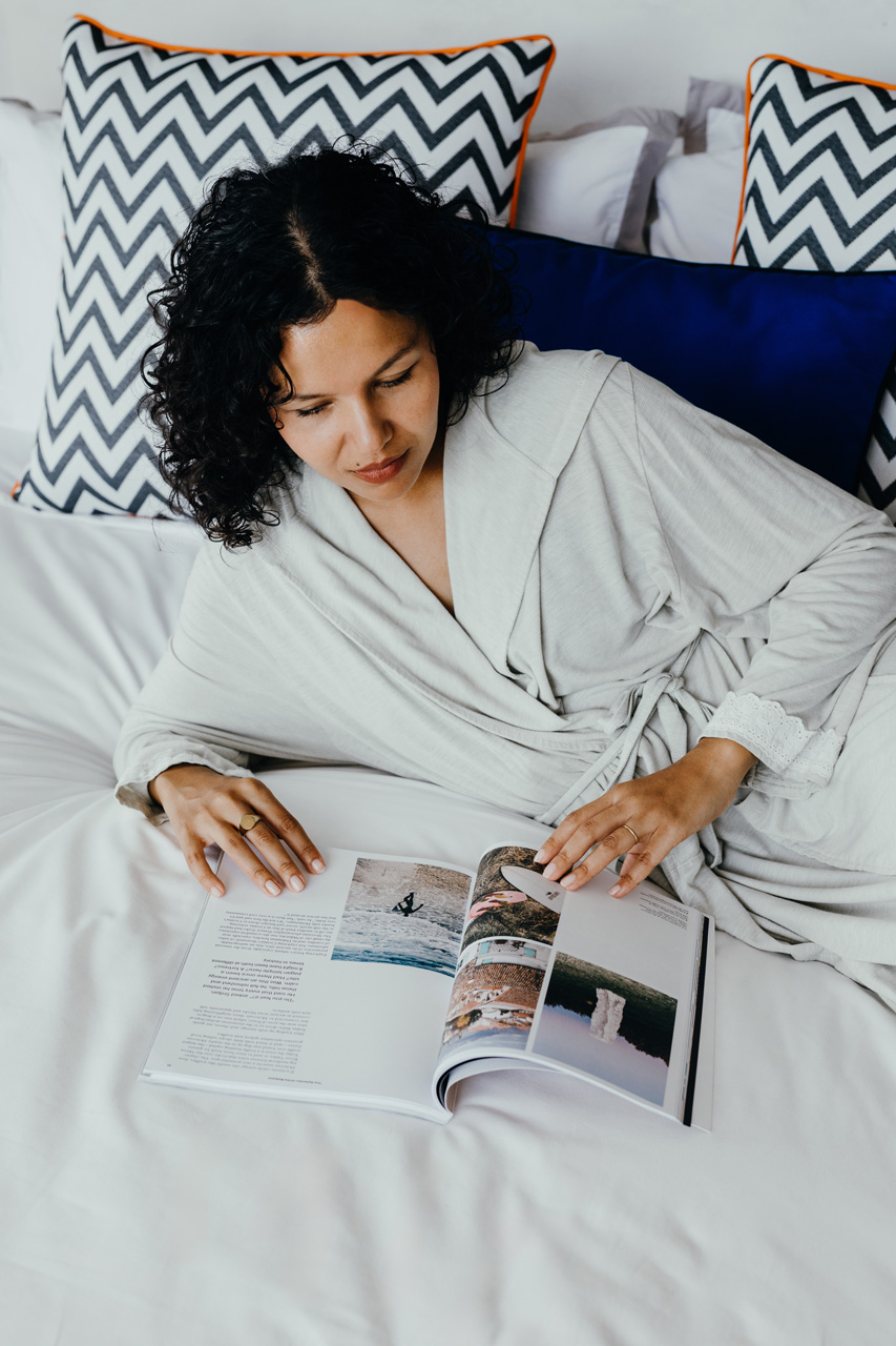 Guest reading on a comfortable bed with colourful cushions.