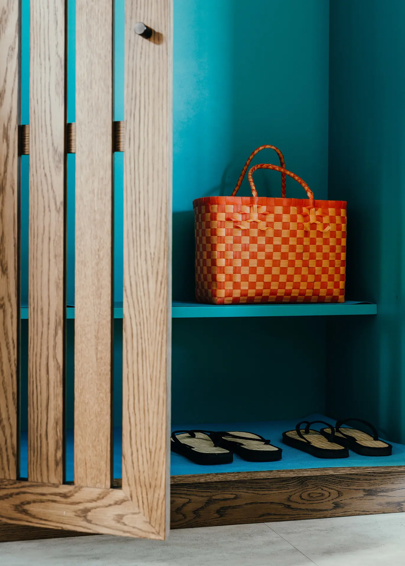 Hotel wardrobe with a woven beach bag and sedge & cinnamon slippers.