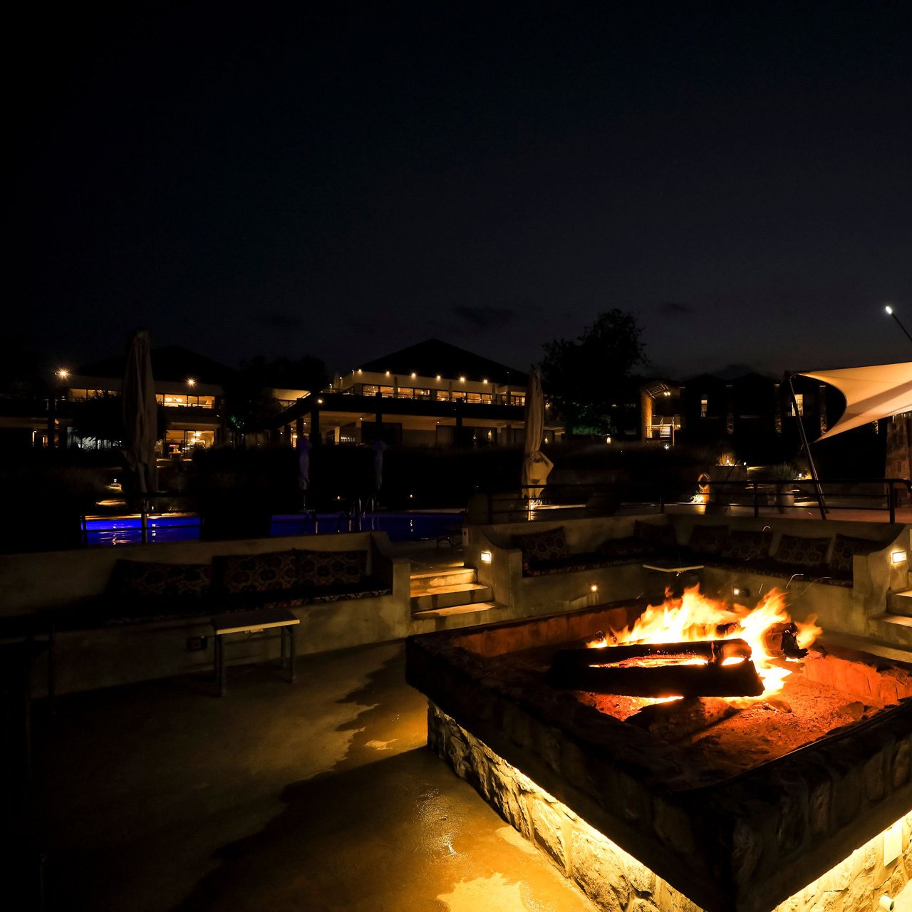 Fire pit and pool area at night at SALT of Akagera.