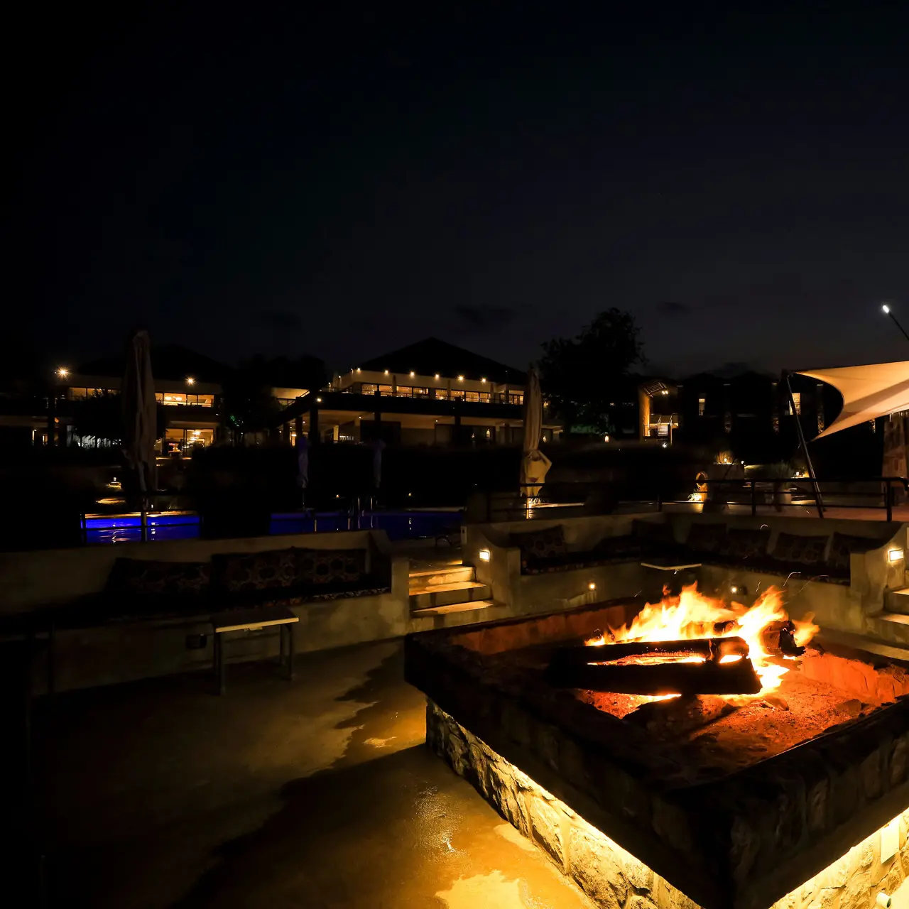 Fire pit and pool area at night at SALT of Akagera.