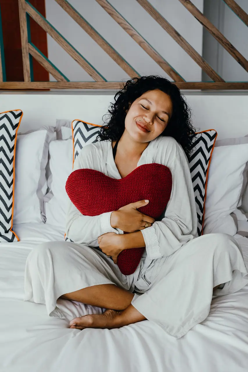 Guest relaxing on the bed with a heart-shaped cushion.