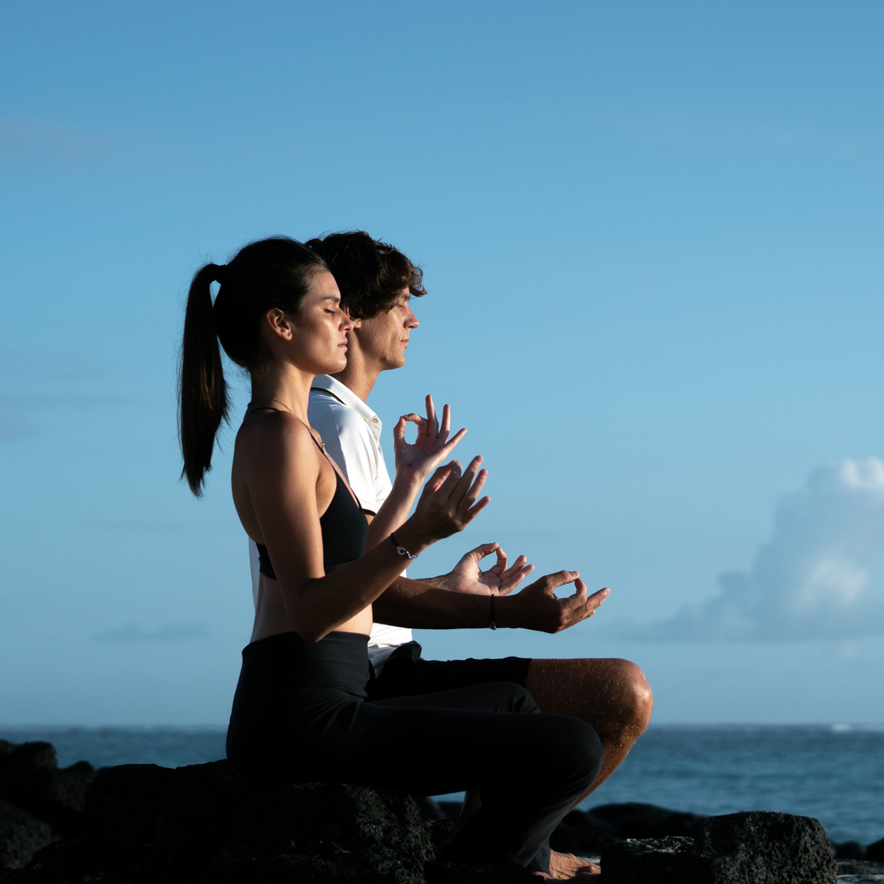 Couple meditating by the ocean.