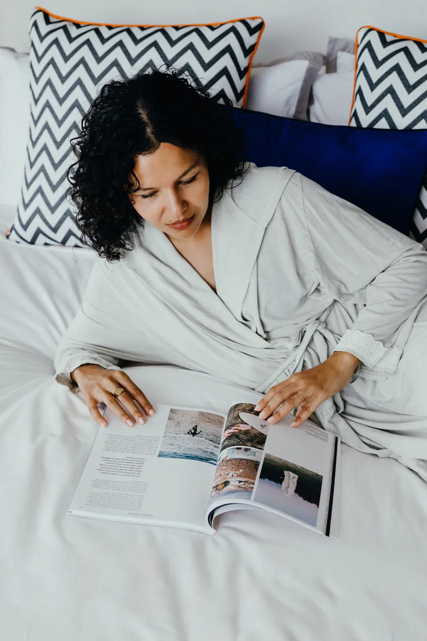 Guest reading on a comfortable bed with colourful cushions.