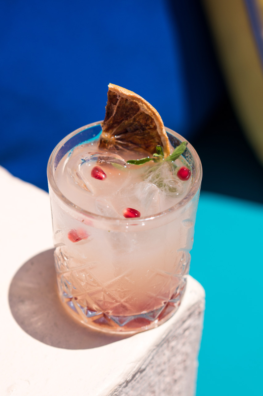 Signature cocktail with citrus, pomegranate and fresh herbs over ice.