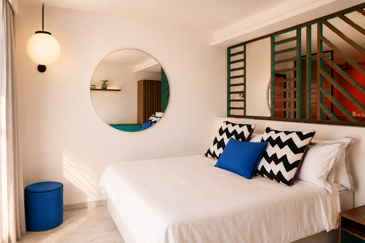 Contemporary hotel room with a king-size bed, bold geometric accents, and an open-plan bathroom design.