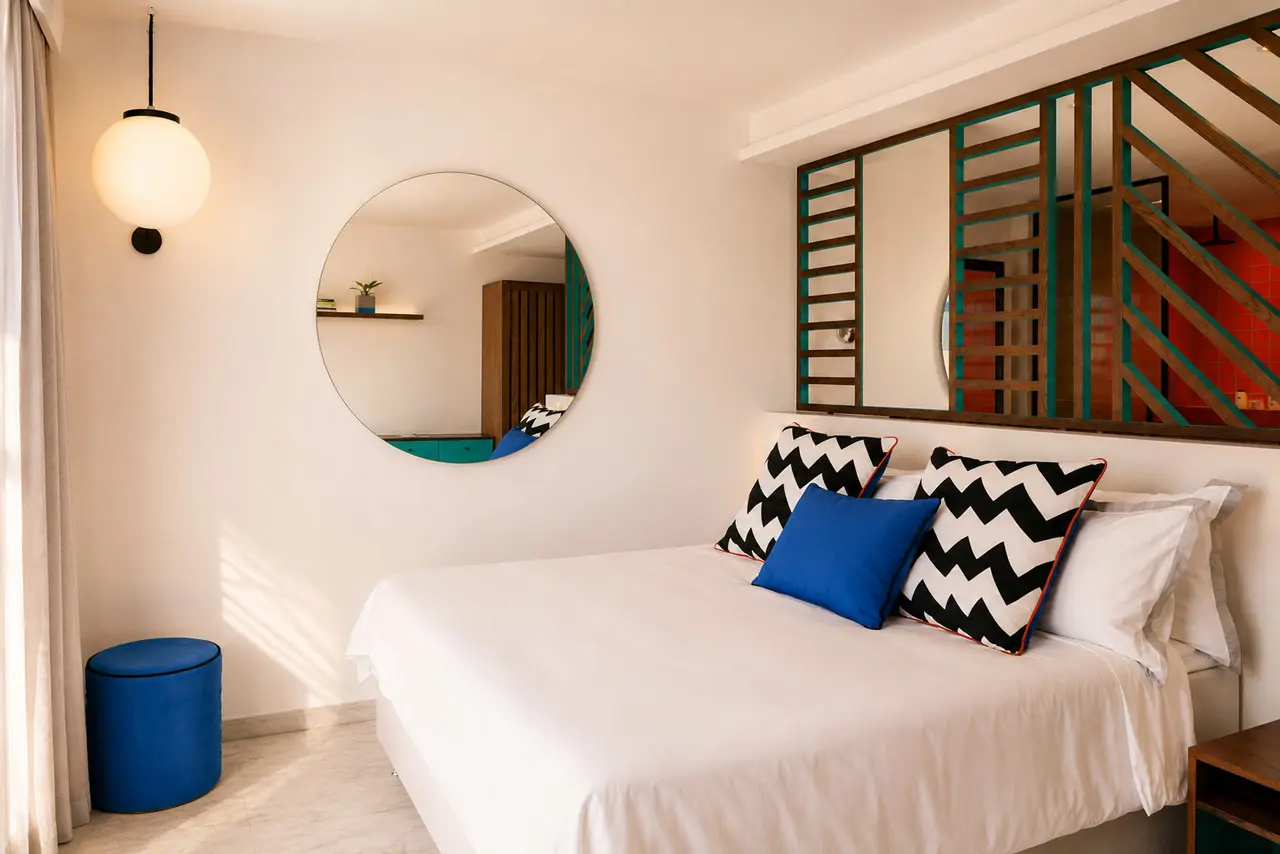 Contemporary hotel room with a king-size bed, bold geometric accents, and an open-plan bathroom design.