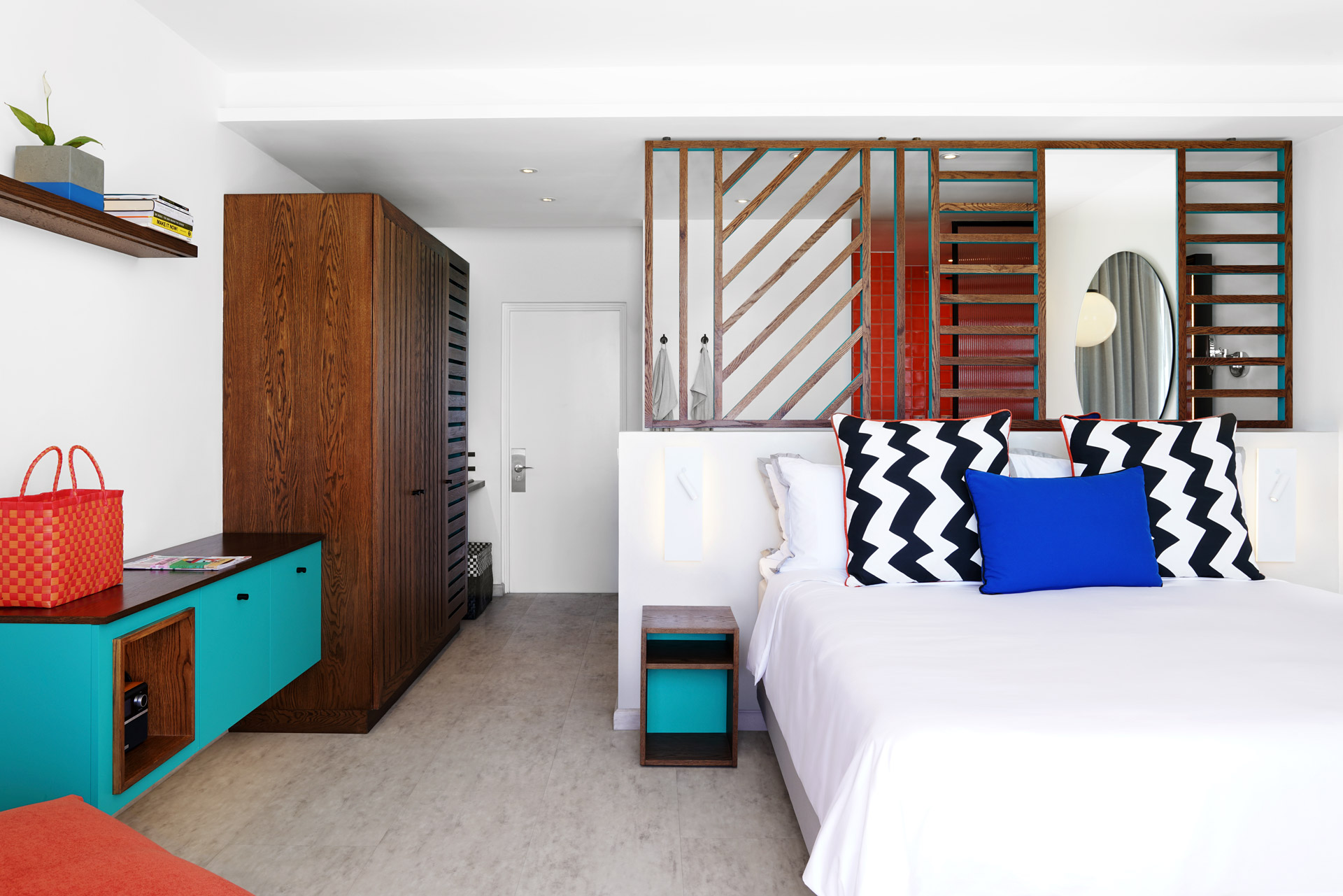 Contemporary hotel room with a king-size bed, bold accents, and open-plan design.