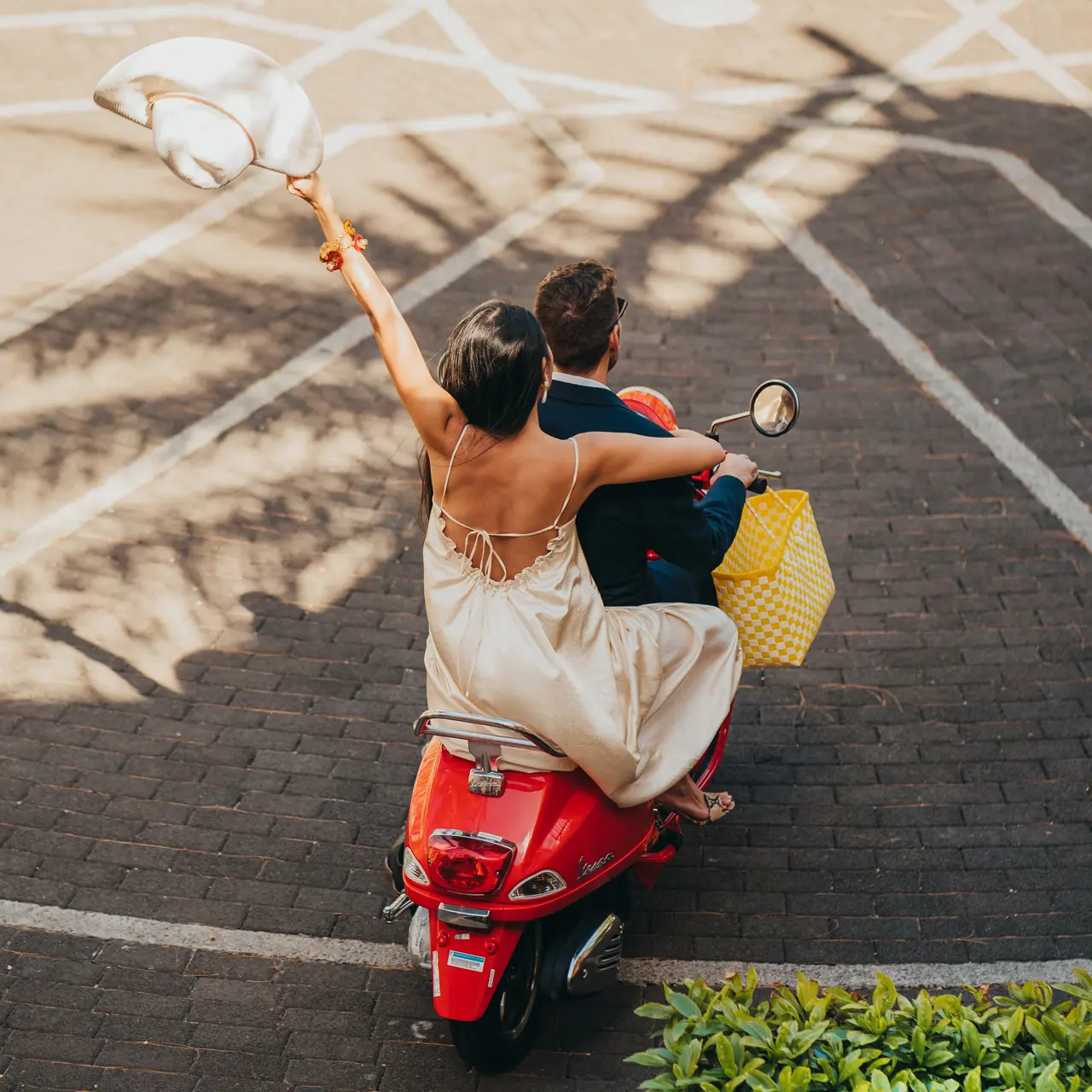 Newlyweds riding a red Vespa through the resort.
