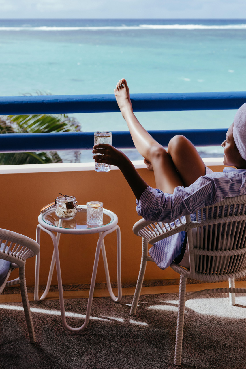 Moment de détente avec un verre sur un balcon face à l’océan.
